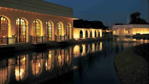 A building with arched windows and a reflection in the water. - The Oberoi Vanyavilas, Ranthambore (Sawai Madhopur)