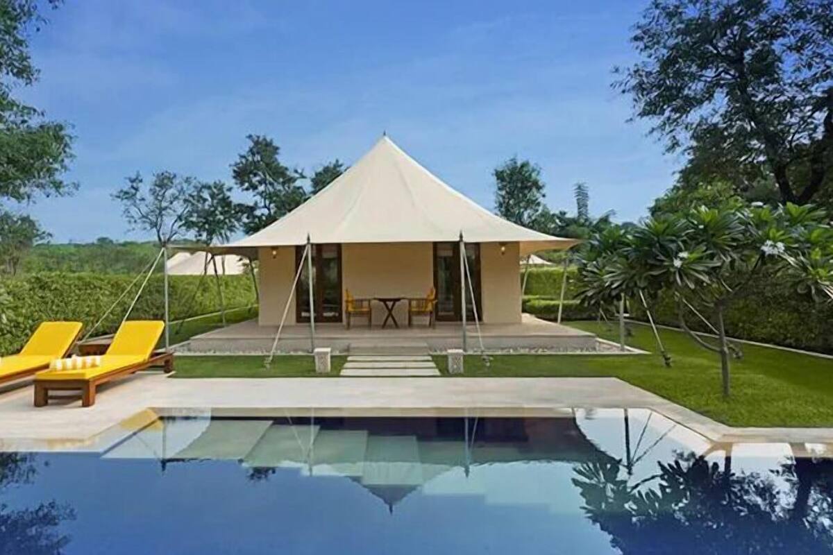 Une villa moderne dotée d’une piscine, de chaises longues jaunes et d’un espace salon extérieur abrité.