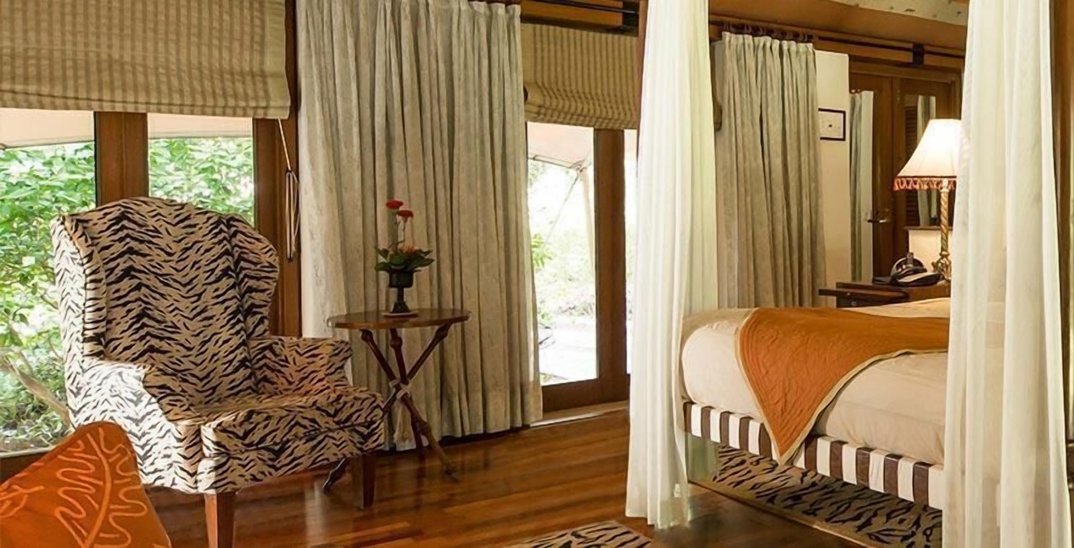 A room with a bed, a chair, a small table, and curtains.