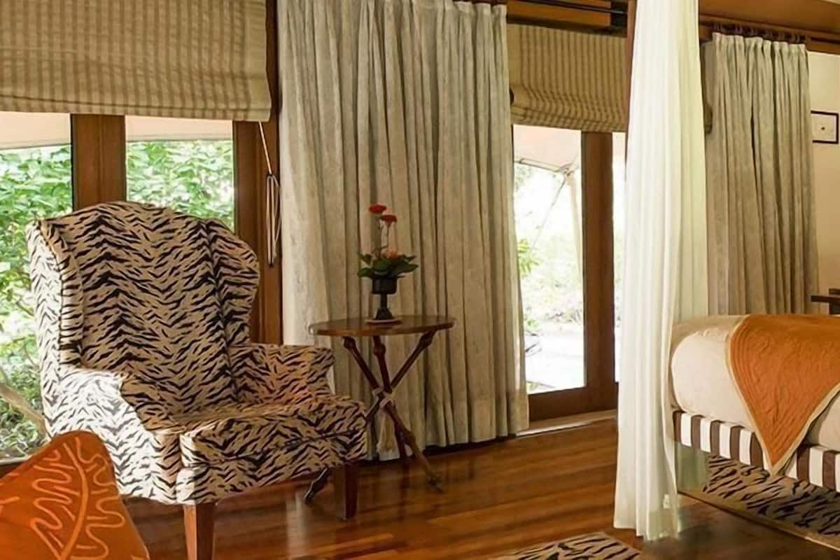 A room with a bed, a chair, a small table, and curtains.