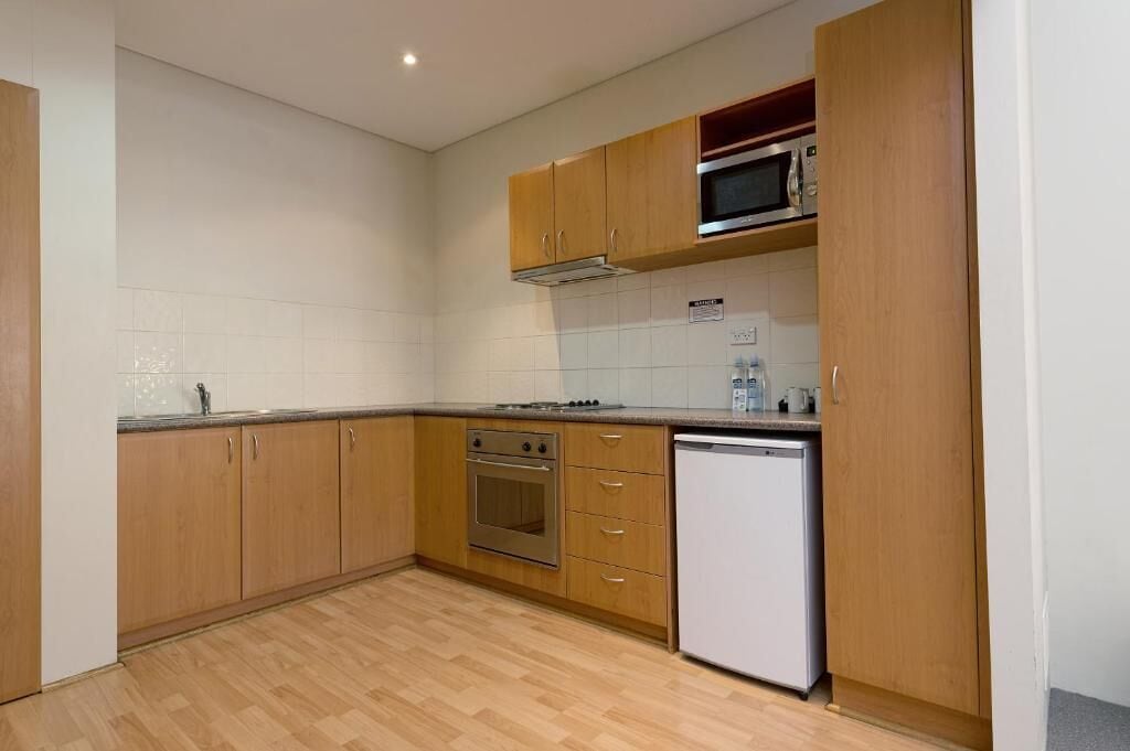 A kitchen with wooden cabinets, a microwave, an oven, and a dishwasher.