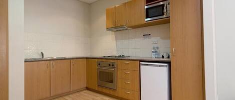A kitchen with wooden cabinets, a microwave, an oven, and a dishwasher.