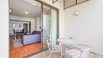 Un espacio de estar moderno con sofá, una mesa de comedor y sillas, un balcón con puerta de cristal y vista al interior.