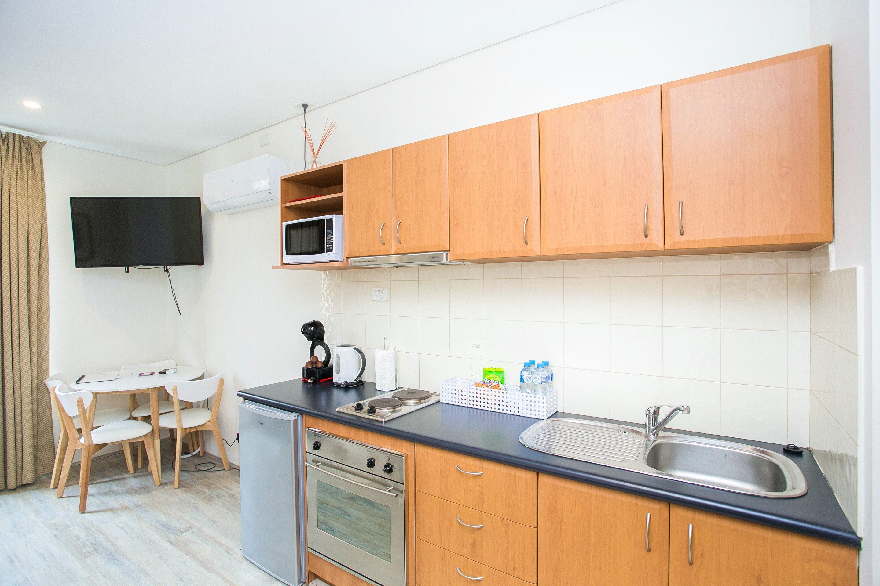 Une cuisine de taille réduite, dotée de meubles en bois, d’un four à micro-ondes, d’une cuisinière et d’un évier.