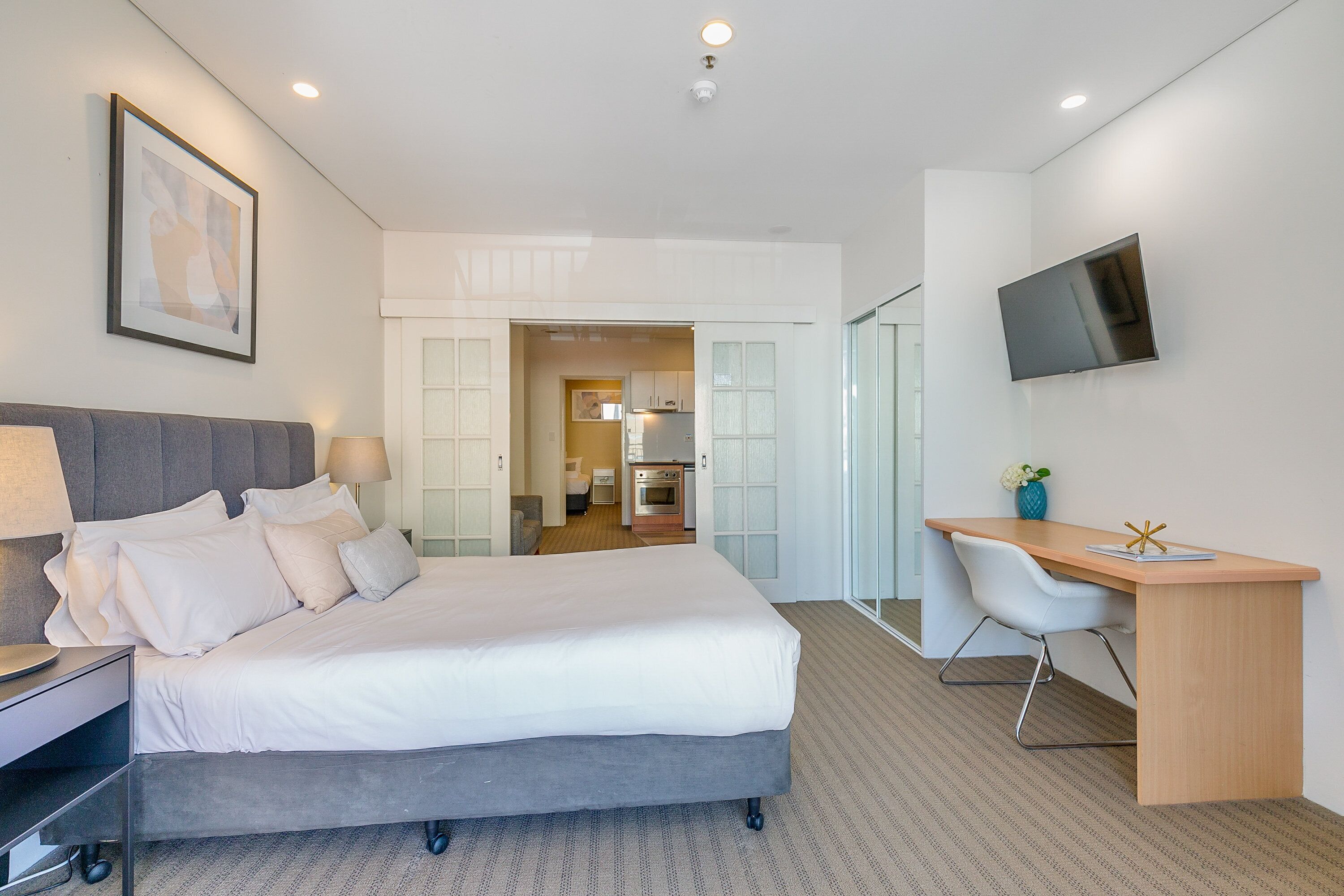 A modern hotel room with a large bed, a desk, and a TV.
