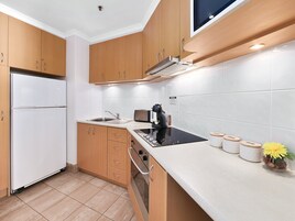 Una cocina moderna con armarios de madera, horno empotrado, pileta y cocina por inducción negra.