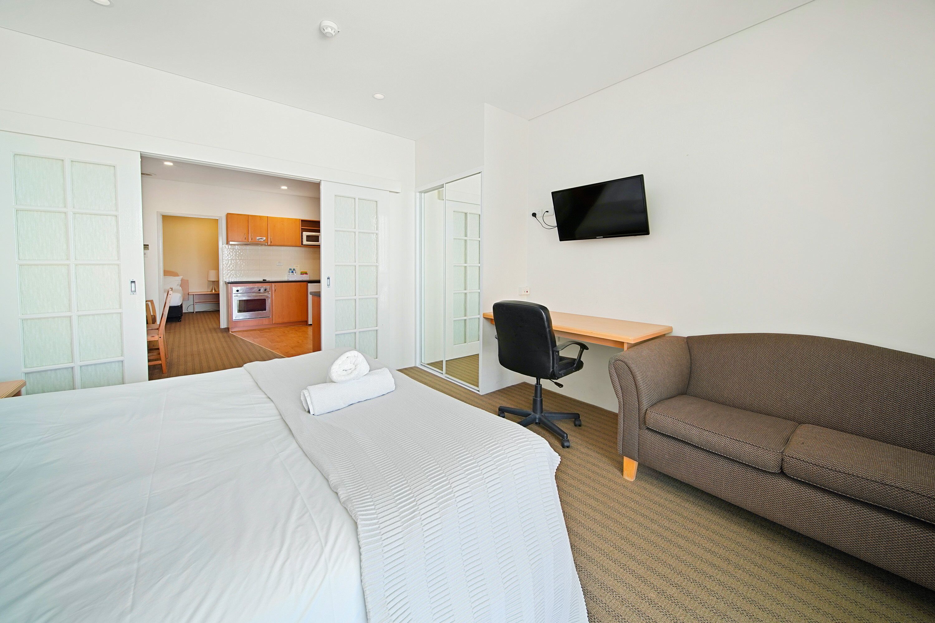 Una habitación de hotel con cama, sofá, escritorio y televisión.