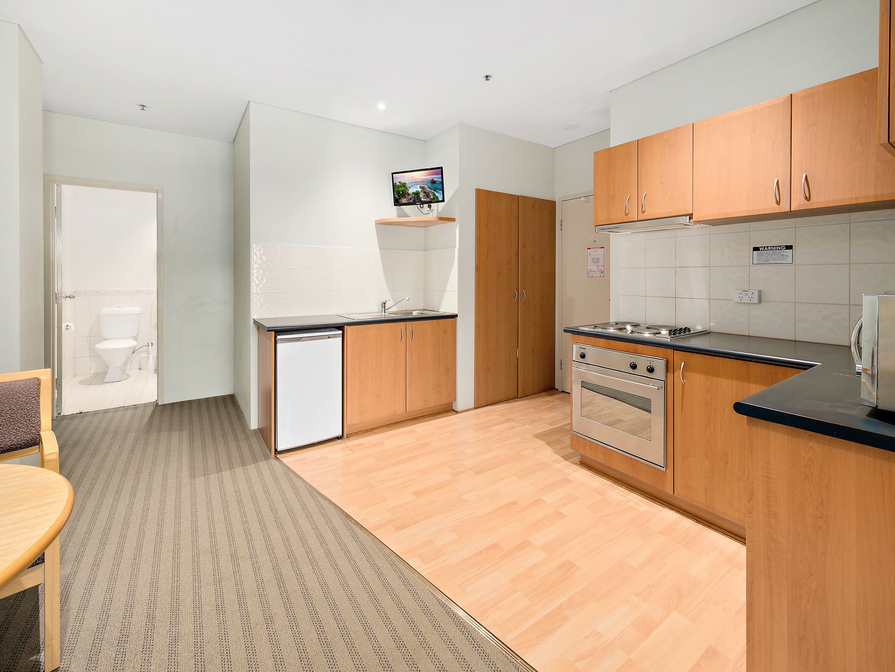 A modern kitchen with wooden cabinets, a built-in oven, and a dishwasher.