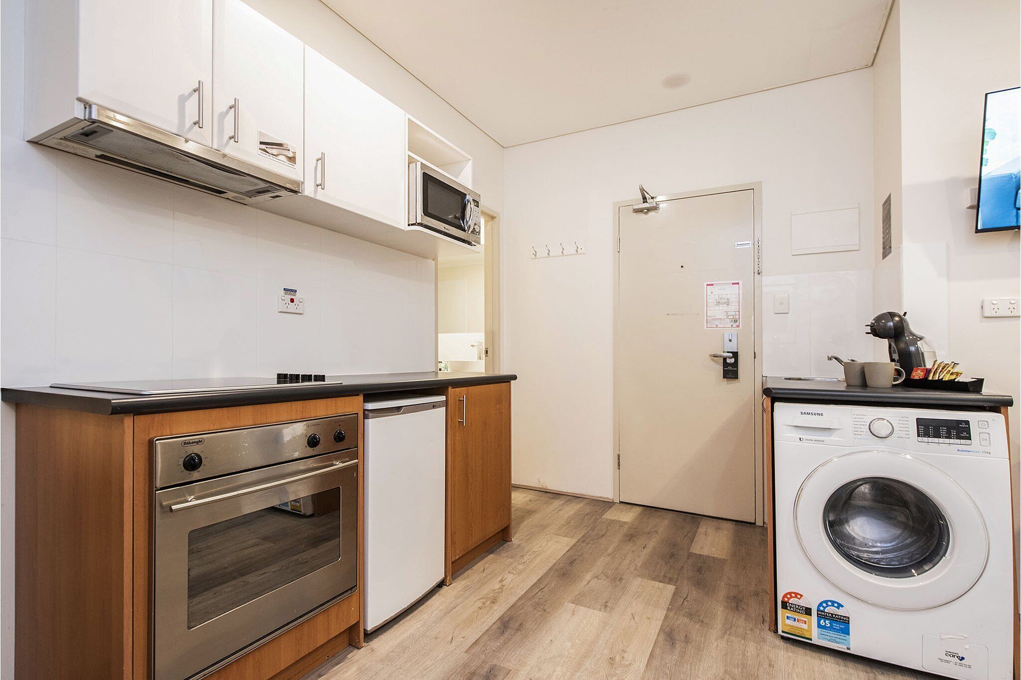A compact kitchen with a microwave, oven, and washing machine.
