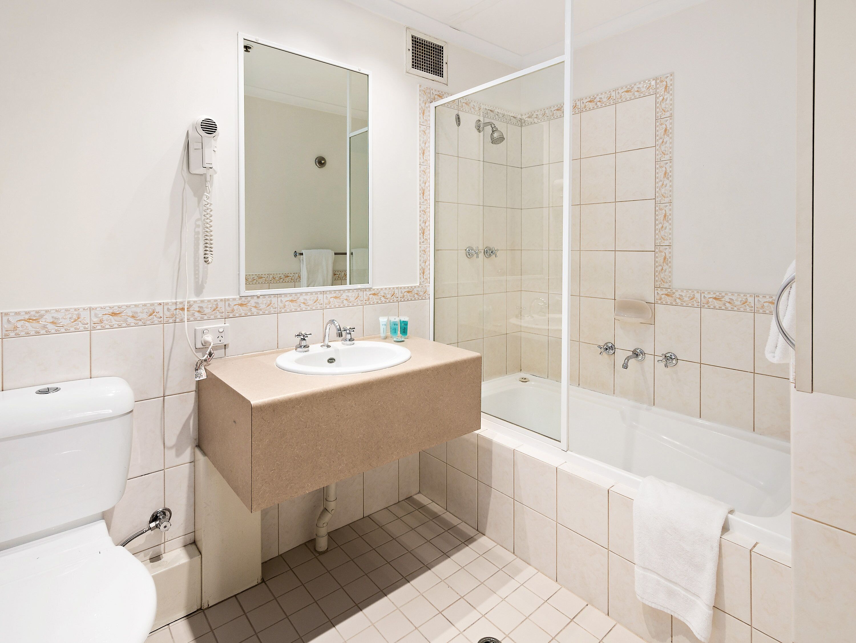 A bathroom with a sink, mirror, toilet, and shower.