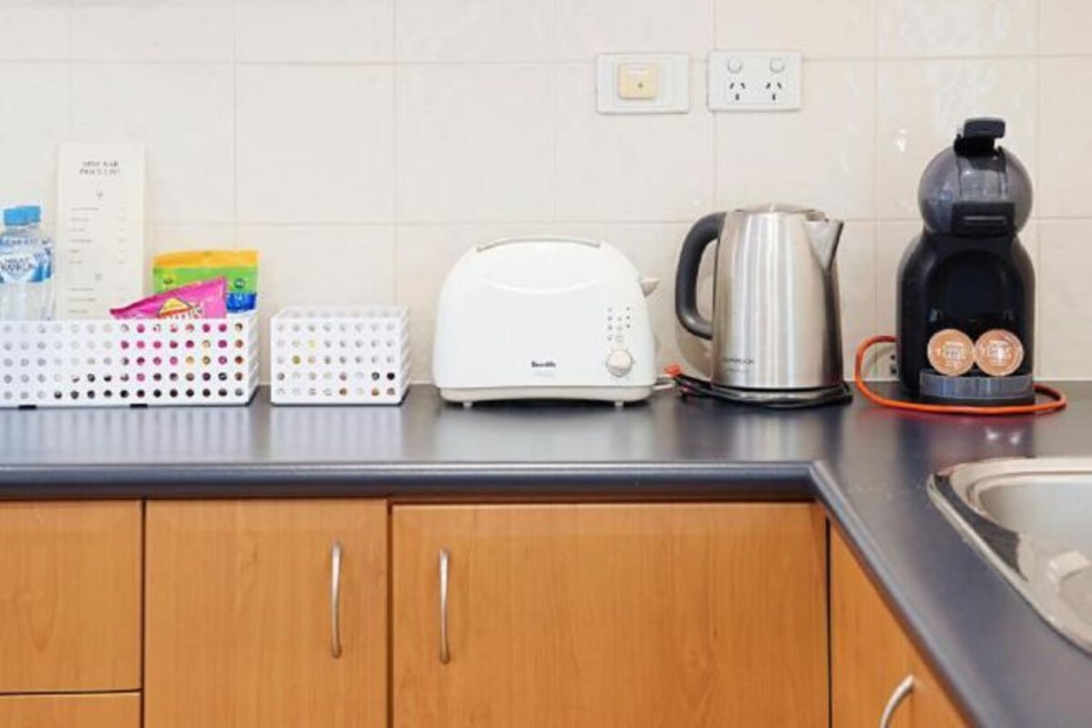 A kitchen with a toaster, kettle, coffee maker, and a water dispenser.