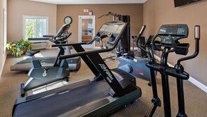 A home gym with various exercise equipment including treadmills, a stationary bike, and a rowing machine. - Apple Tree Inn, SureStay Collection by Best Western (Petoskey)
