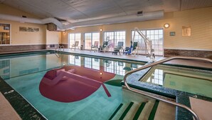 An indoor swimming pool with clear water, a lifeguard station, and a sunlit room with windows and seating. - Apple Tree Inn, SureStay Collection by Best Western (Petoskey)