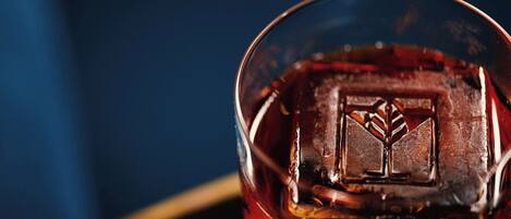 A close-up of a glass with a clear liquid and an ice cube.