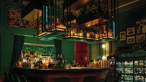 A bar with a green wall, shelves of bottles, and a fish tank. - Radisson Blu Carlton Hotel, Bratislava (Bratislava)