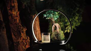 A circular display with a bonsai tree and a glass of water.