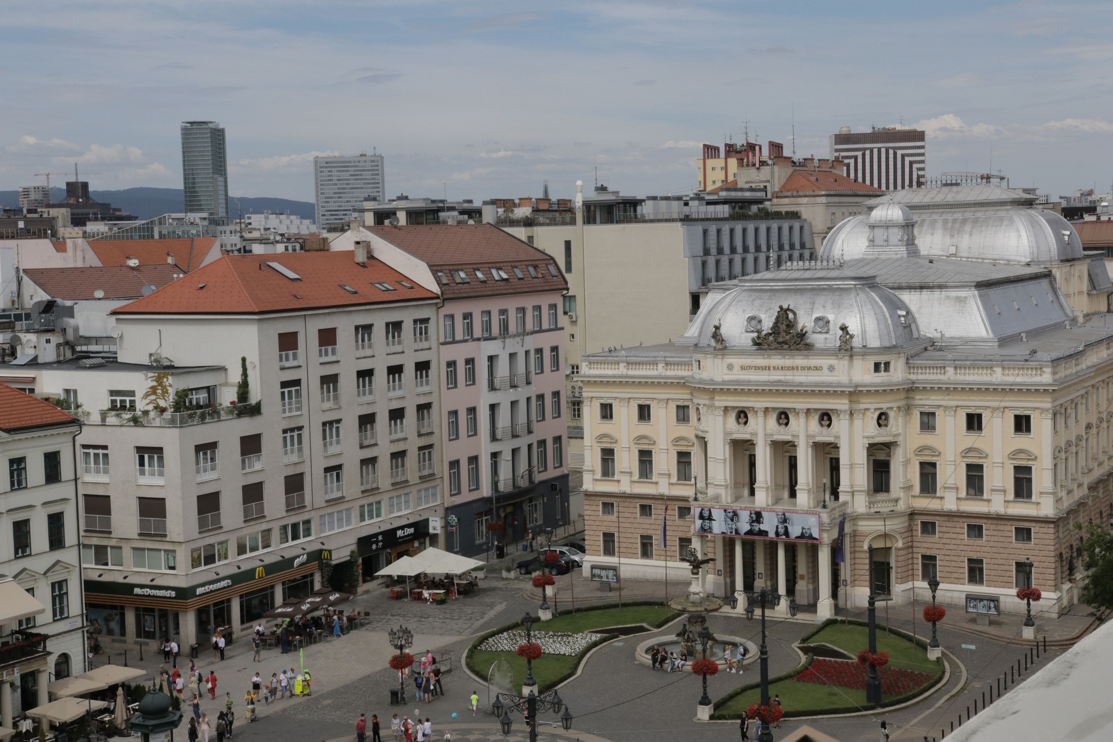 Un edificio histórico con arquitectura clásica, un patio central con fuente y edificios modernos circundantes.