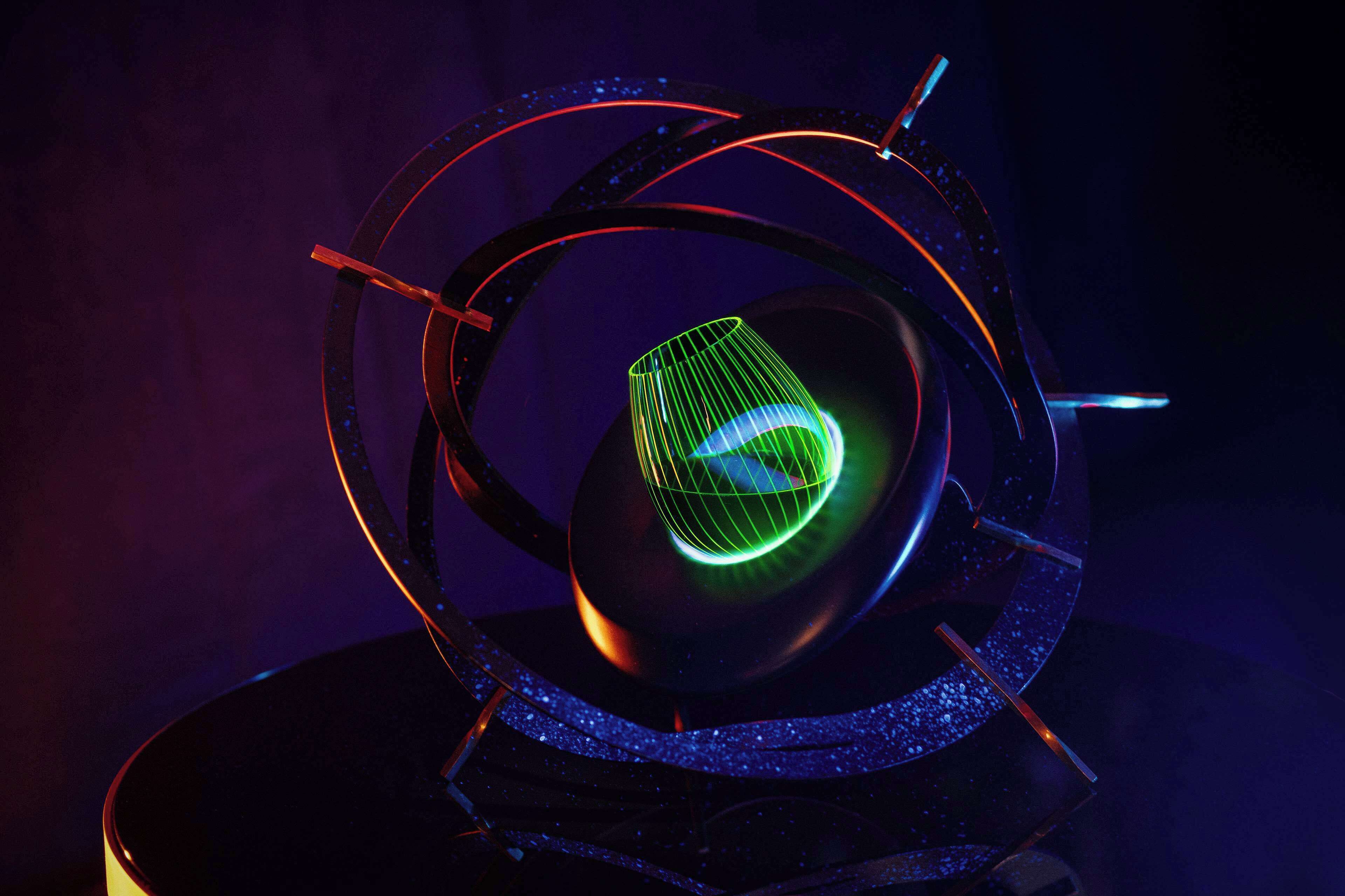 A spherical object with a glowing green grid pattern, surrounded by a dark structure with red and blue accents.