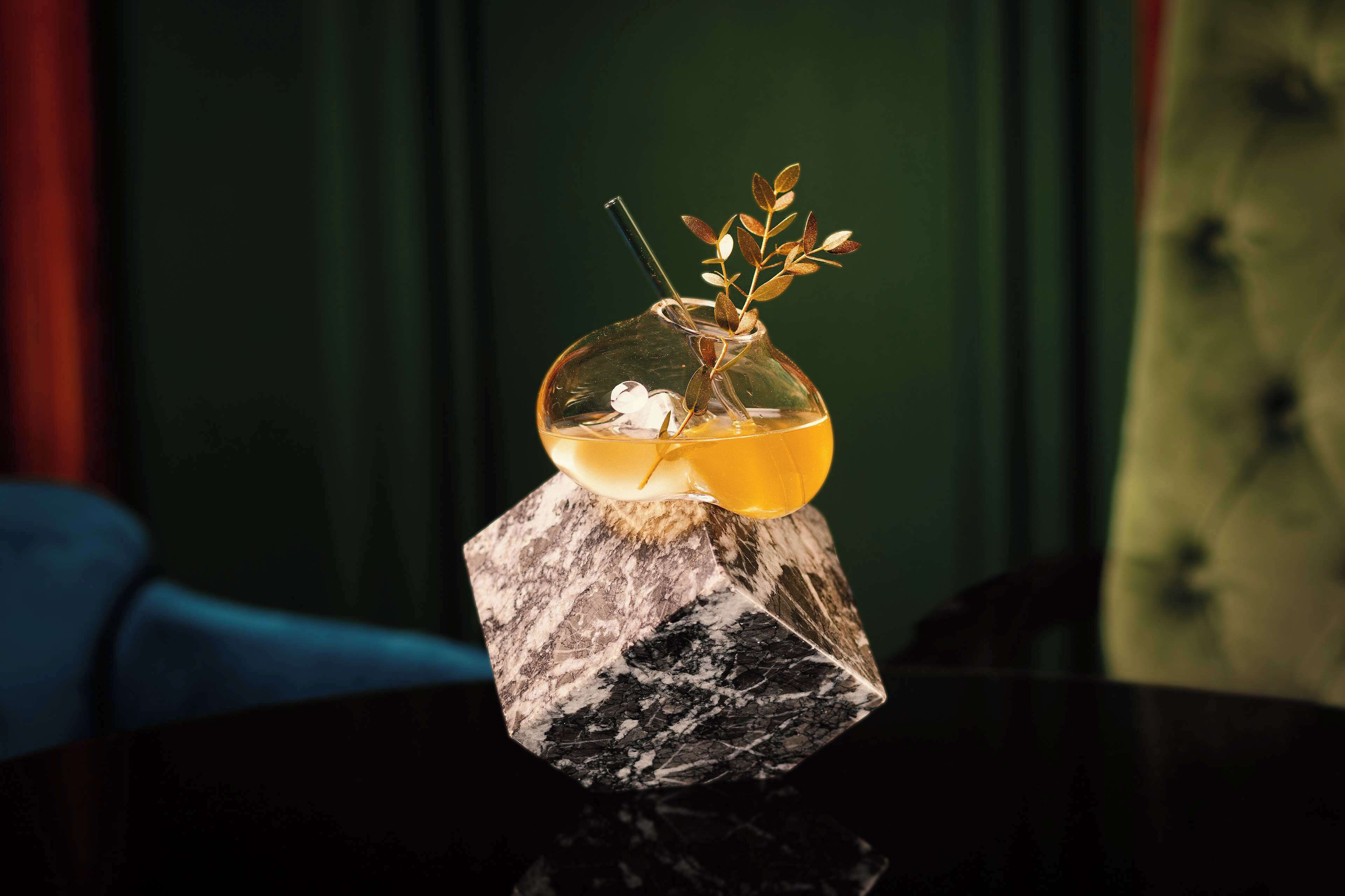 A clear glass vase with a plant on a marble pedestal.