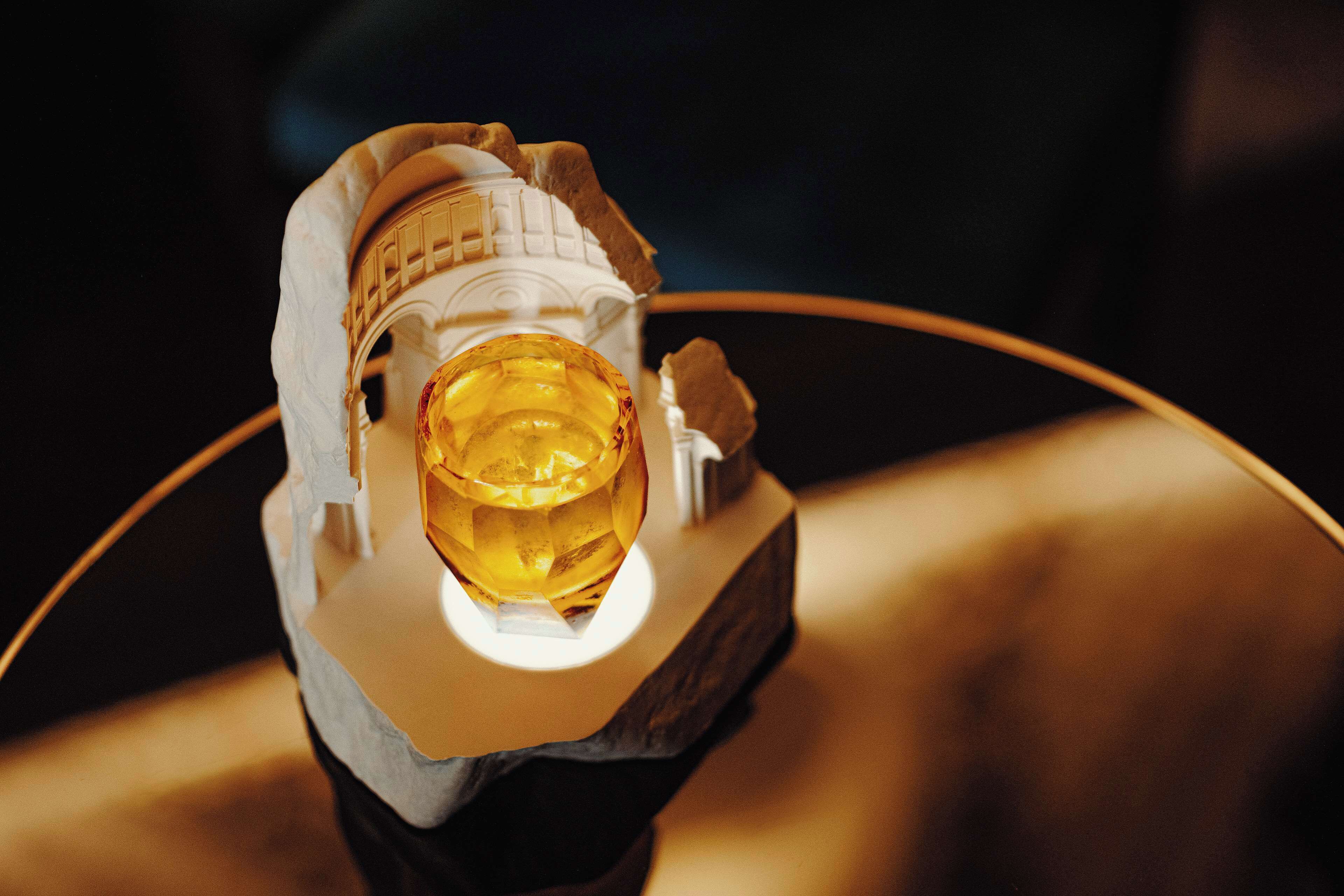 A model of a spacecraft with a golden orb at its center, displayed on a curved stand.