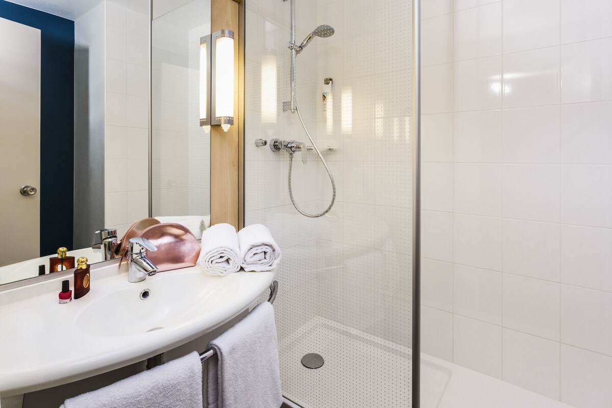 A modern bathroom with a glass-enclosed shower, a white sink, and a mirror.