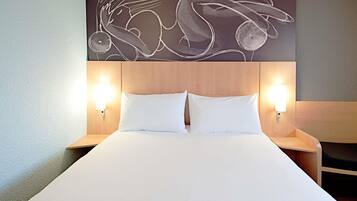 Een hotelkamer met een groot bed, twee nachtkastjes en een kunstwerk aan de muur.