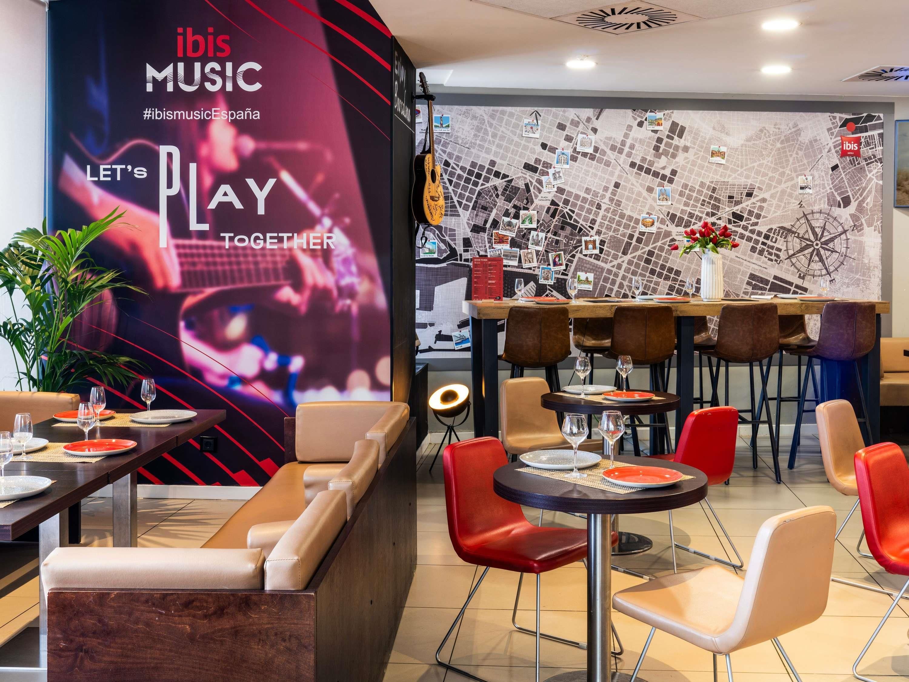 Een restaurant met een modern interieur, met een grote muur met een muurschildering over muziek, meerdere zithoeken met een mix van tafels en hoekbanken, en een decoratieve wereldkaart.