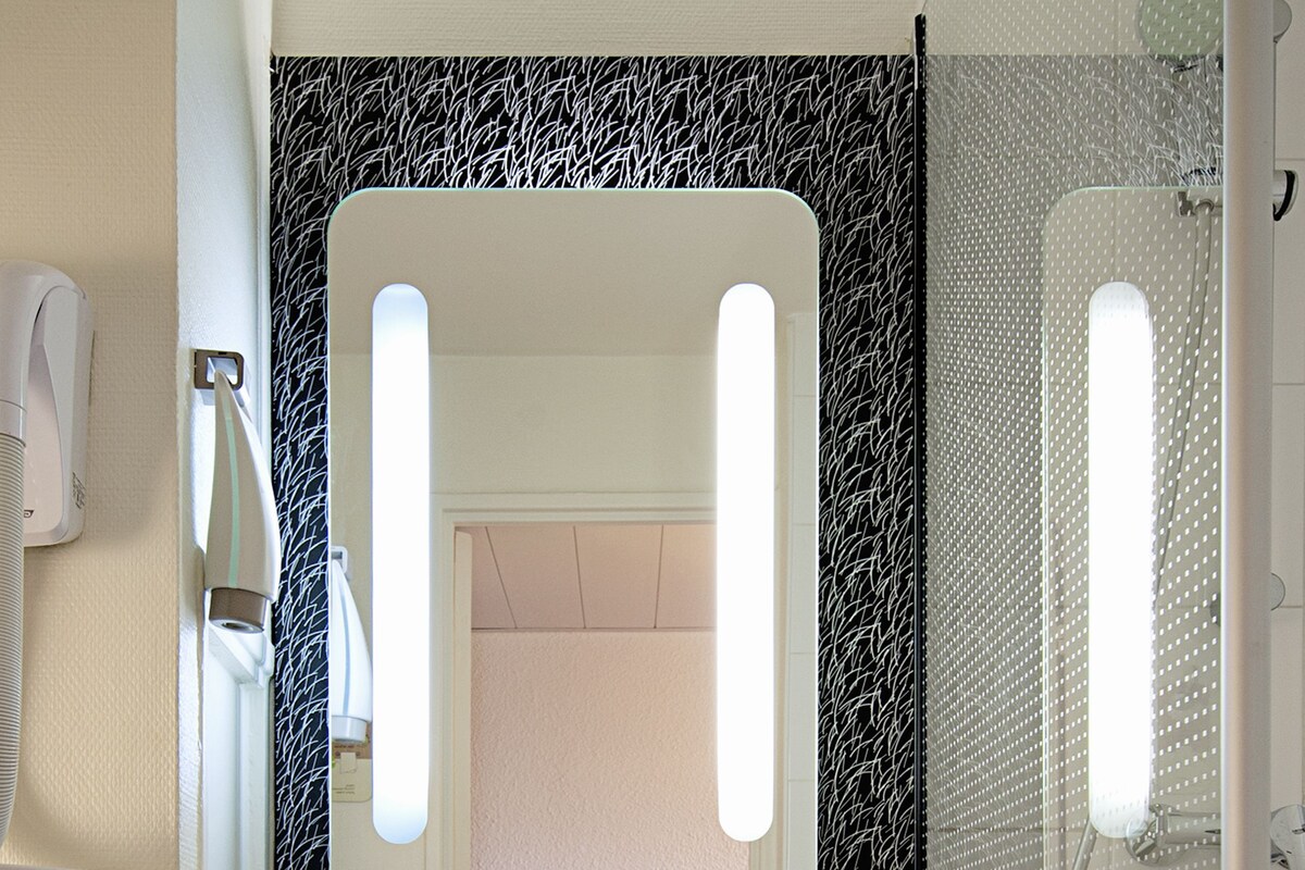 A bathroom with a white sink, a mirror, a towel rack, and a shower area.