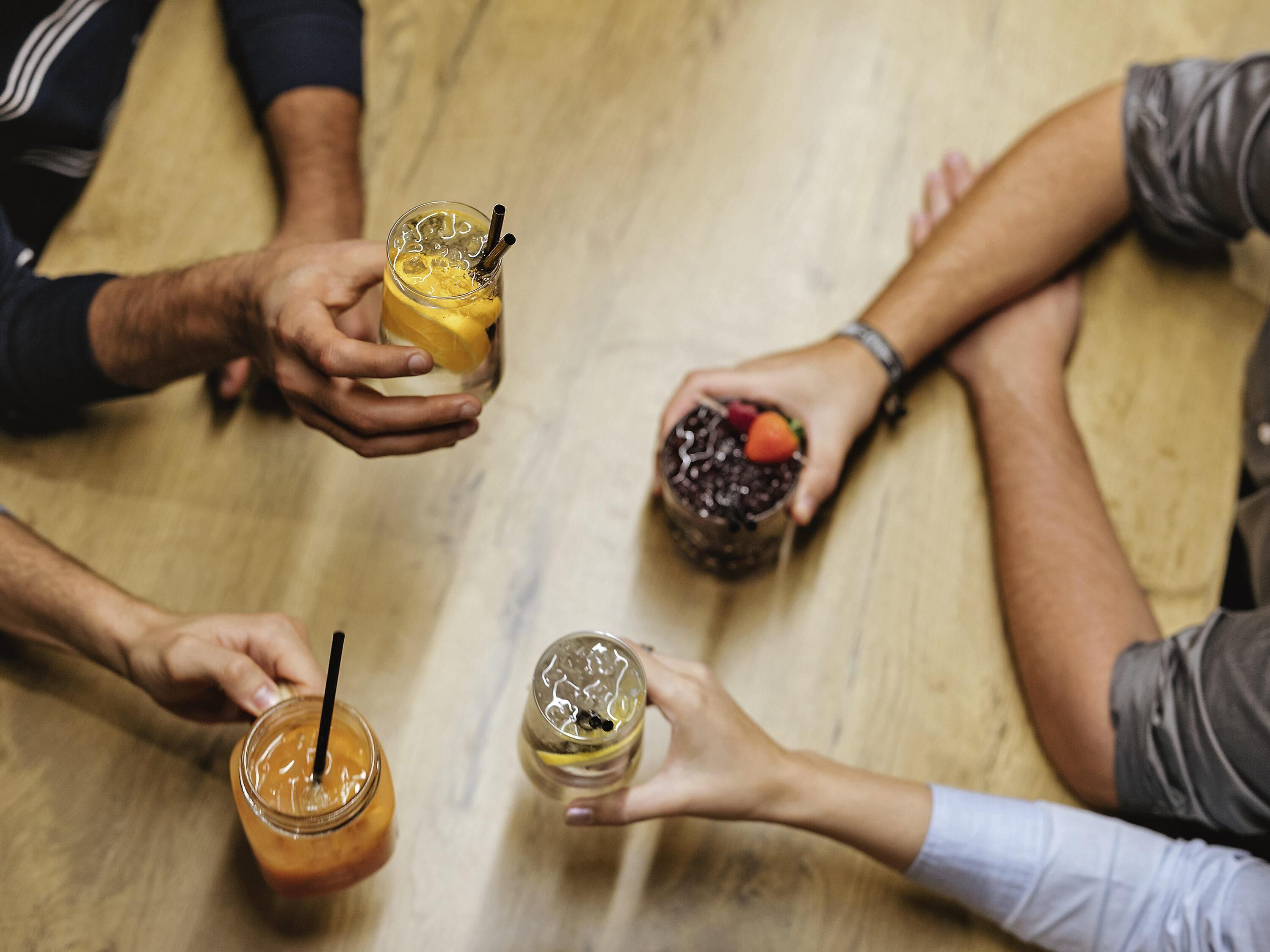 A group of people holding drinks around a table.
