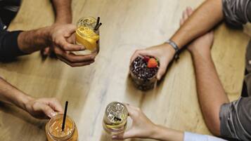 A group of people holding drinks around a table.