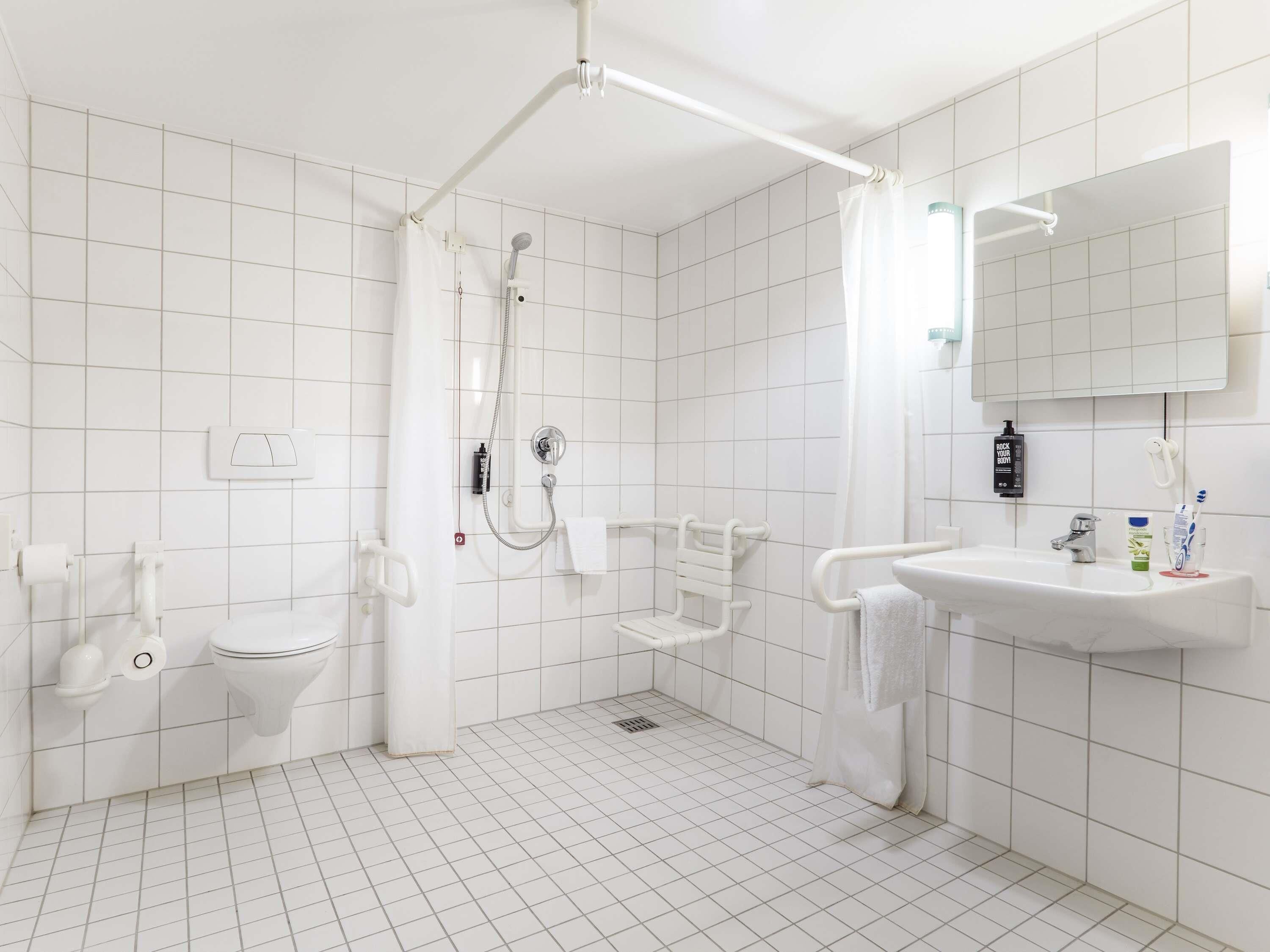 Une salle de bain moderne avec une douche, des toilettes et un lavabo, le tout dans des tons blancs.