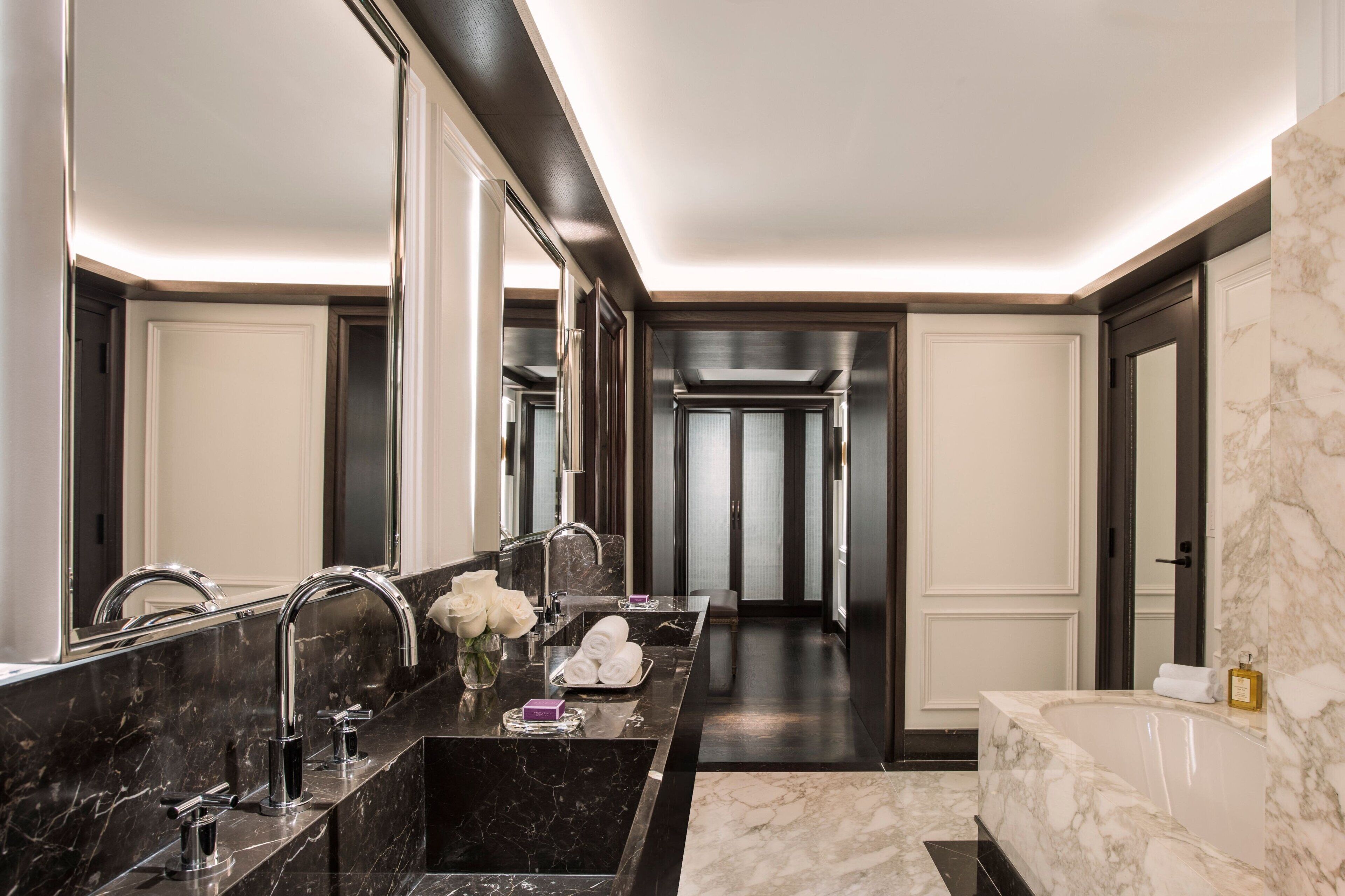A modern bathroom with a black marble sink, a large mirror, and a separate bathtub.