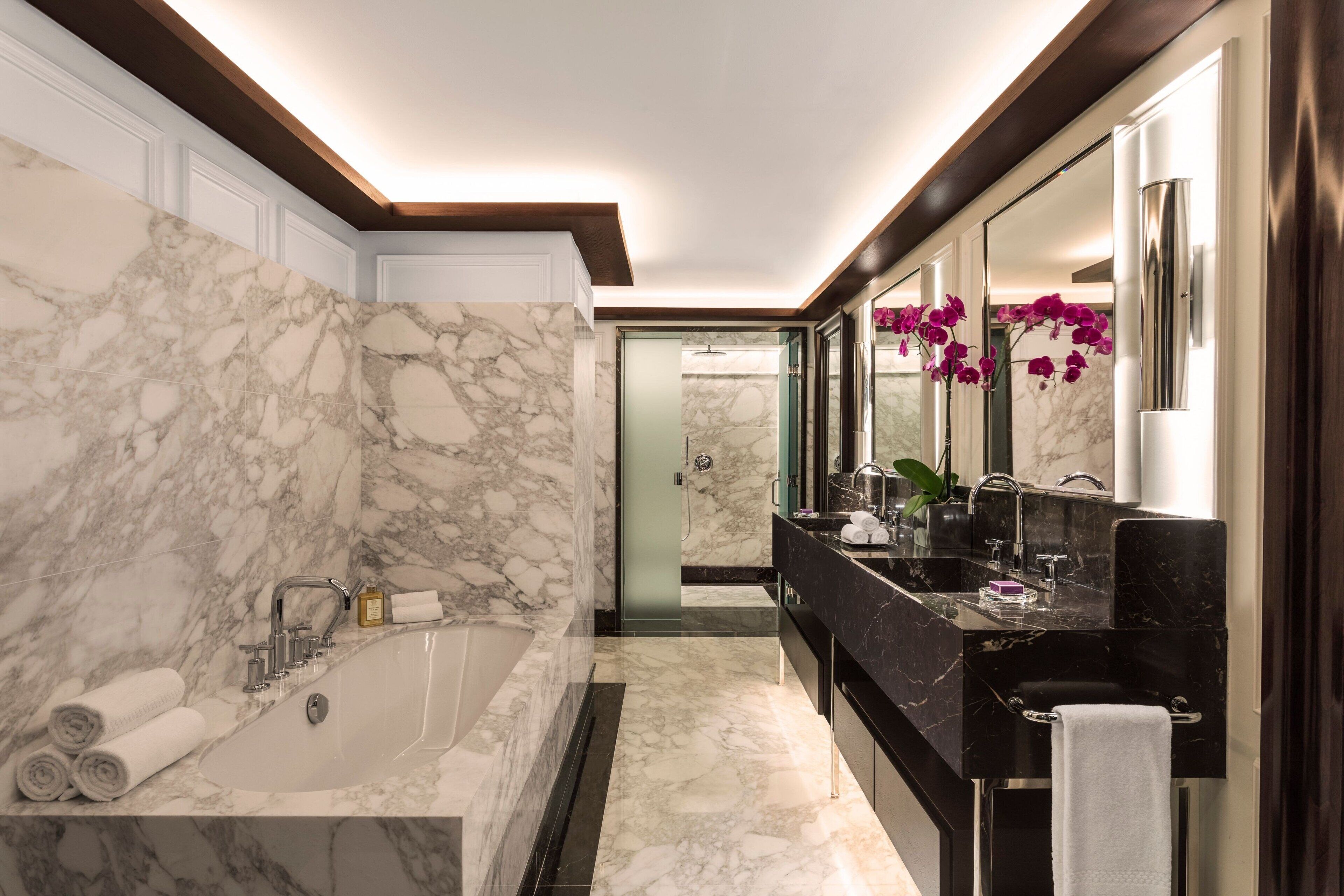 A modern bathroom with a marble sink, a bathtub, and a large mirror.
