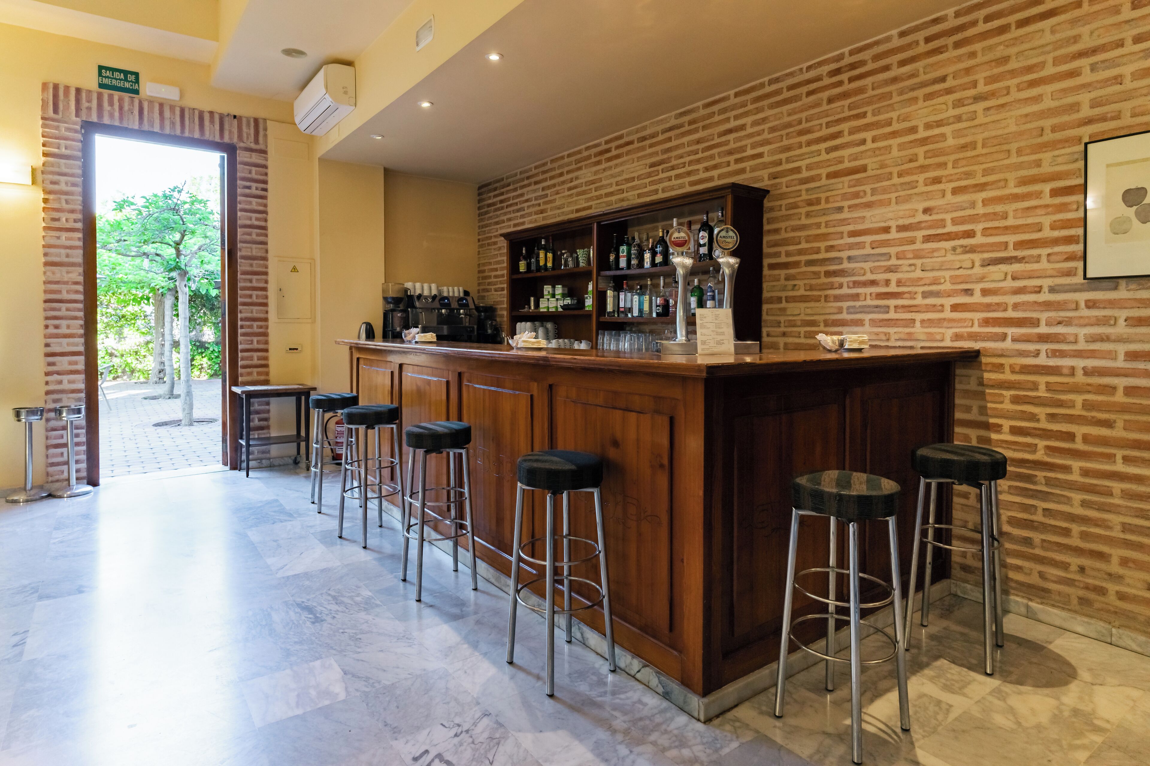 A bar area with a brick wall, wooden counter, and bar stools.
