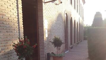 A brick building with a covered entrance and potted plants.