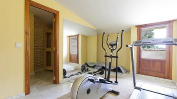 Un gimnasio en casa con una elíptica, una bicicleta estática y pesas sueltas.