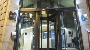 El exterior del Hotel Zenit, con una entrada de vidrio y un letrero sobre las puertas.