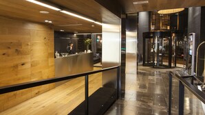 Un vestíbulo moderno con paneles de madera, un mostrador de recepción y una puerta giratoria.