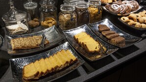 A buffet with various food items including pastries, cakes, and cookies.