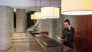 A modern reception area with a long counter, large pendant lights, and a wooden cabinet. - Hotel RH Murcia Centro By Hoteles RH (Murcia)