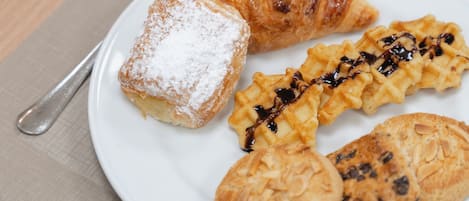 A plate with pastries and a cup of coffee on a table.