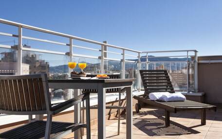 A rooftop terrace with a table, chairs, and a sun lounger.