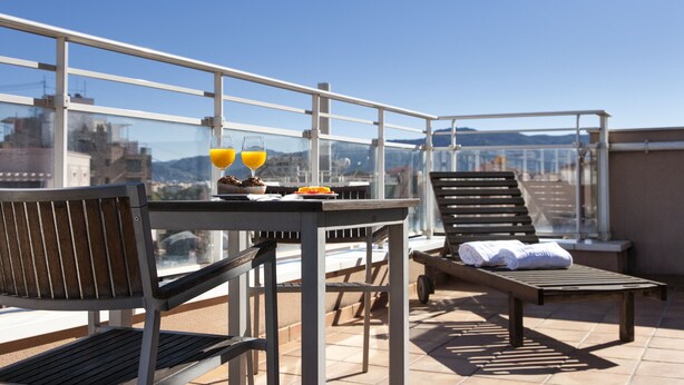 A rooftop terrace with a table, chairs, and a sun lounger. - Hotel RH Murcia Centro By Hoteles RH (Murcia)