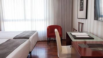 Een hotelkamer met twee bedden, een bureau, een stoel en een televisie.