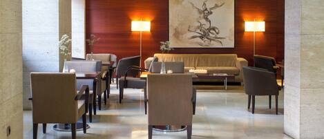 A lobby with a seating area, a large abstract painting, and two wall-mounted lamps.