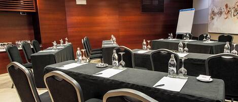 Un salón de conferencias con varias mesas, sillas y una pizarra.