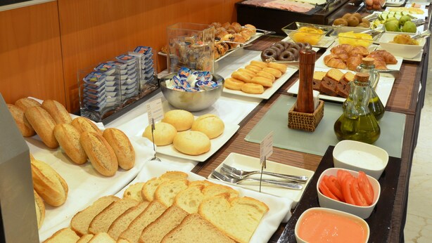 A buffet with various food items including bread, pastries, fruits, and condiments.