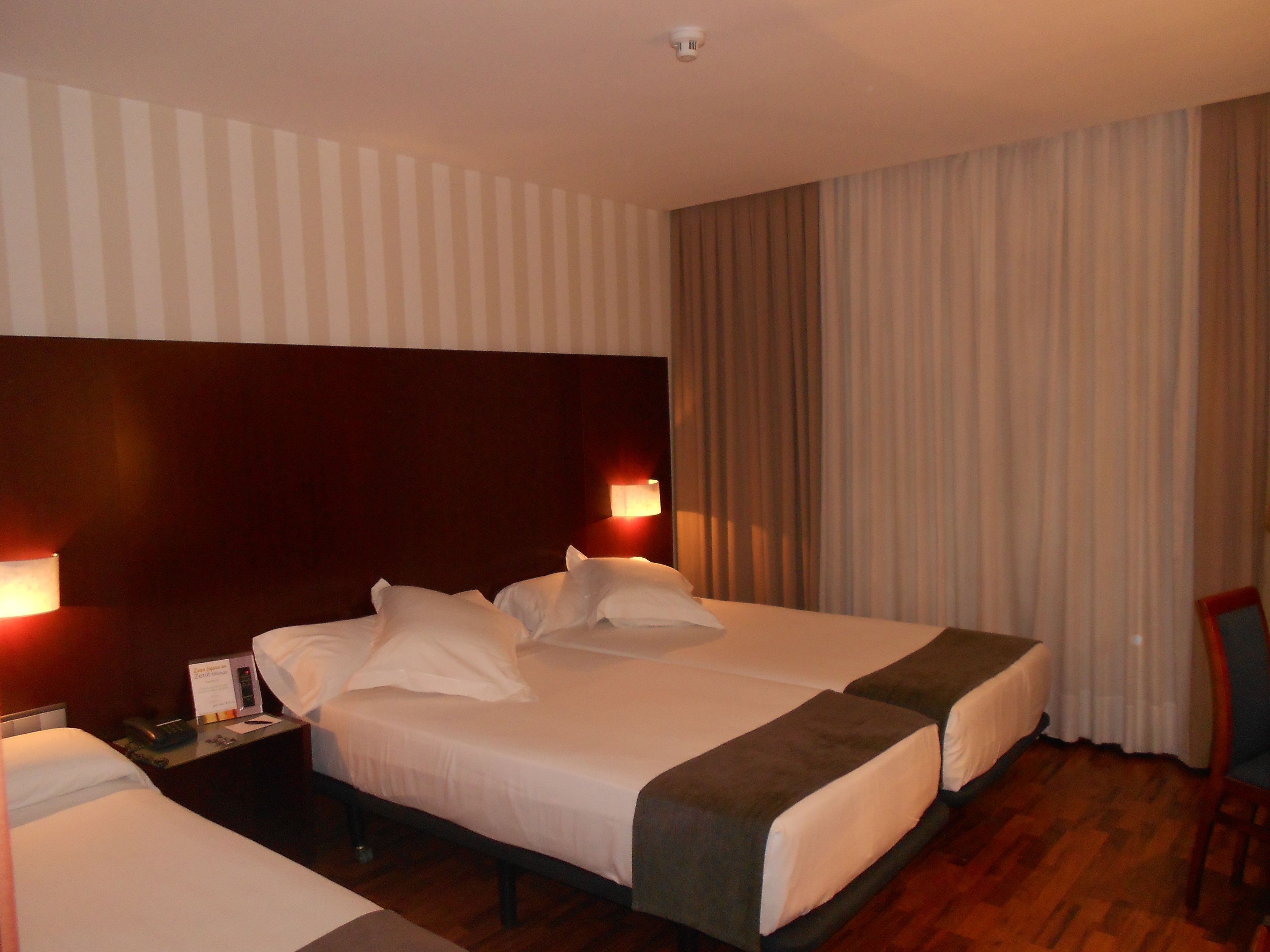 A hotel room with a large bed, two bedside tables, a desk, and a chair.