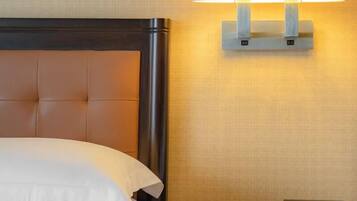 A hotel room with a bed, a nightstand with a lamp, a digital clock, and a telephone.