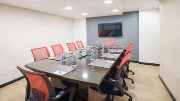 A conference room with a long table, red chairs, and water bottles.